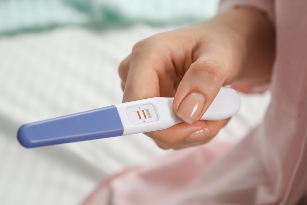 A woman with low AMH holding a positive pregnancy test